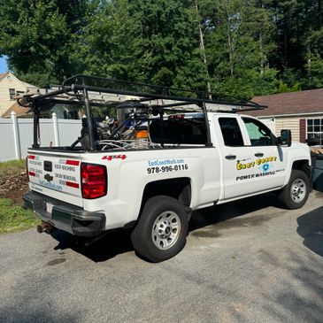 White pickup truck with power washing equipment and business branding.
