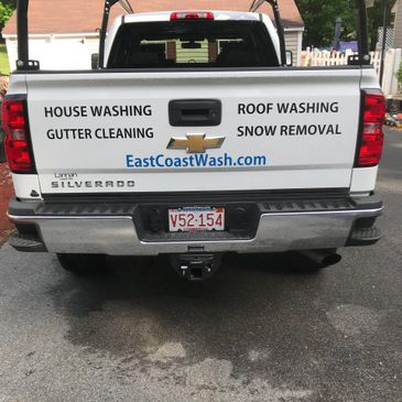 White Chevrolet Silverado truck with house cleaning service advertisement on tailgate.