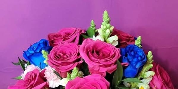 Vibrant bouquet with pink roses and blue flowers.