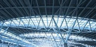 Interior view of a large industrial steel roof structure with skylights.