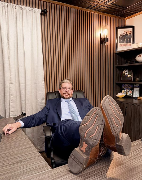 Man in suit relaxing with feet on desk in modern office.
