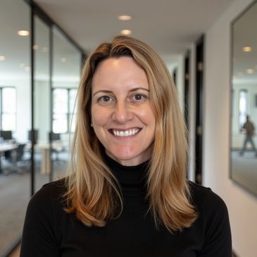 Smiling woman with blonde hair in a black turtleneck inside an office.