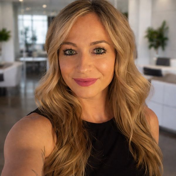 Smiling blonde woman with green eyes in an indoor setting.