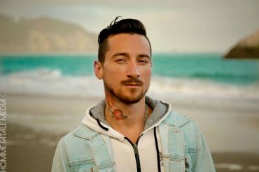 Man with a tattoo on his neck at the beach.