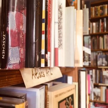 A close-up of books on a wooden shelf with a handwritten label.