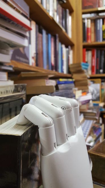 An artificial hand picking a book