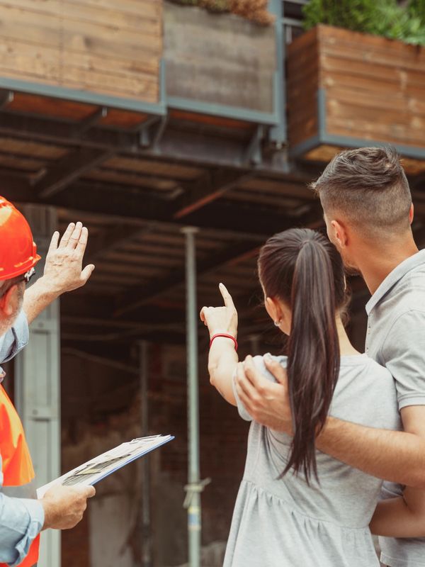 Construction worker explaining building plans to a couple at a construction site.