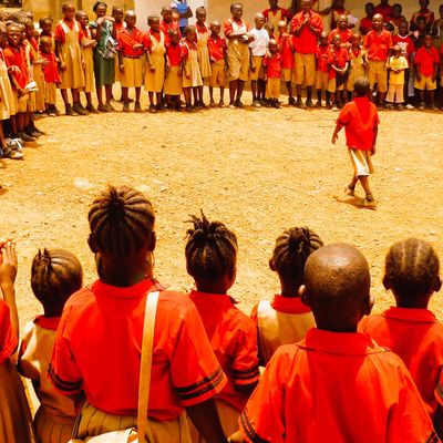 School children in uniform gathered in a large circle outdoors.