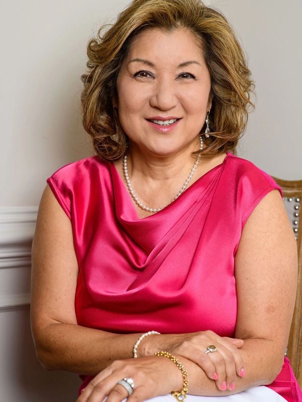 Margaret Kim sitting and smiling in pink shirt