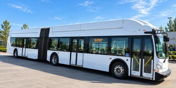 A white articulated city bus parked on a paved area.