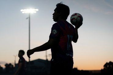 Silhouette of a soccer player preparing for a throw-in during sunset.