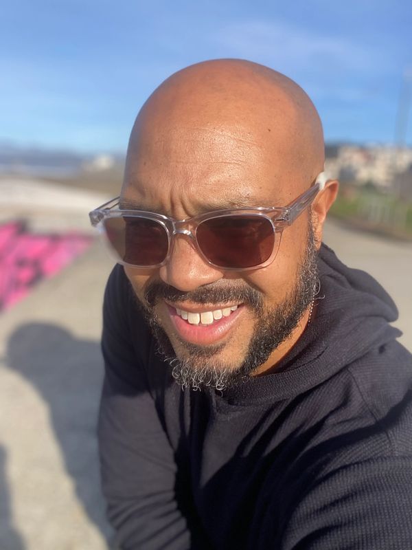 Smiling man with sunglasses enjoying a sunny day outdoors.