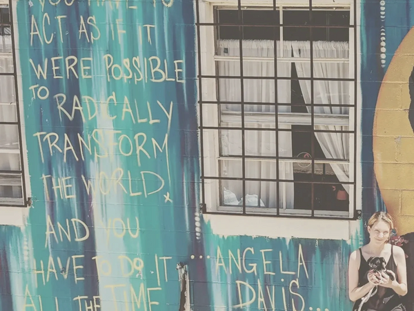 Angela Davis quote on wall in Austin Texas with Cassia Mosdell and her dog sitting beside it. 