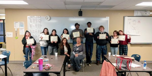 Group of students proudly holding certificates in a classroom.