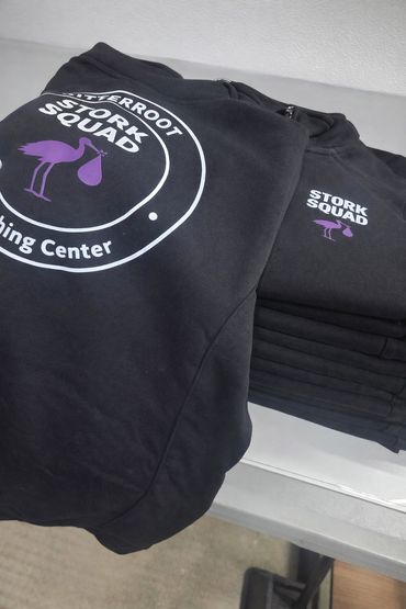 Black hoodies with 'Stork Squad' logo and design.