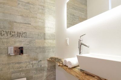 powder room with rustic tile that reads recycle, and vessel sink sitting on rough wood