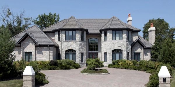 ABBA Construction Group white brick home with black windows, and paver driveway