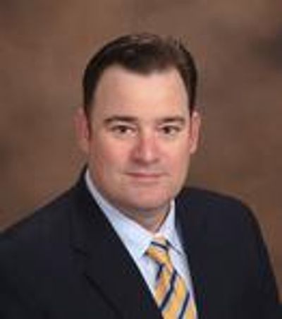 Professional headshot of a man in a suit and striped tie.