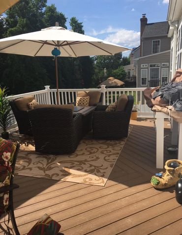 Cozy outdoor patio with wicker furniture and a large umbrella on a sunny day.