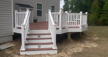 A small wooden deck with white railings attached to a house.