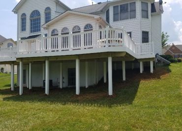 White house with elevated deck supported by multiple posts.