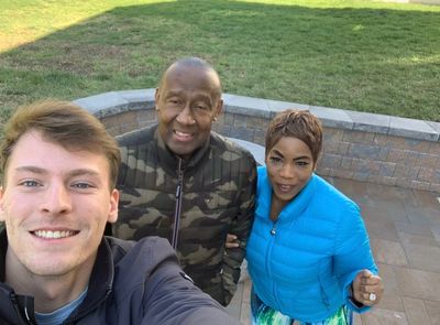 Three people smiling outdoors, taking a selfie in a sunny garden.