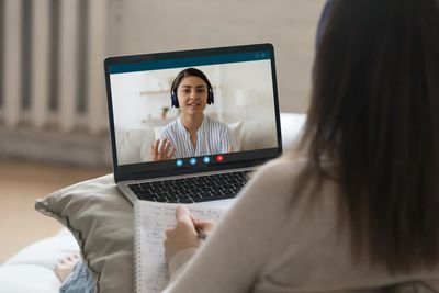 A woman attending a video call while taking notes.