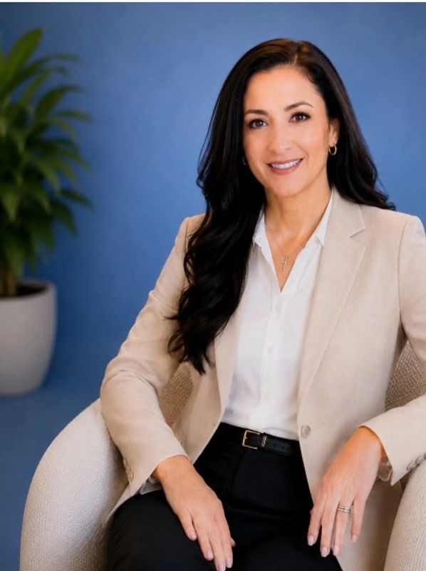 Professional woman smiling in a beige blazer and white shirt.