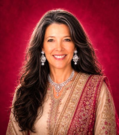Woman wearing traditional Indian attire and jewelry smiling.