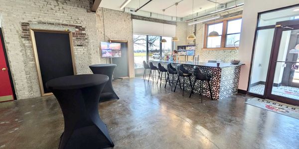 Modern indoor space with bar seating and high tables covered in black cloth.