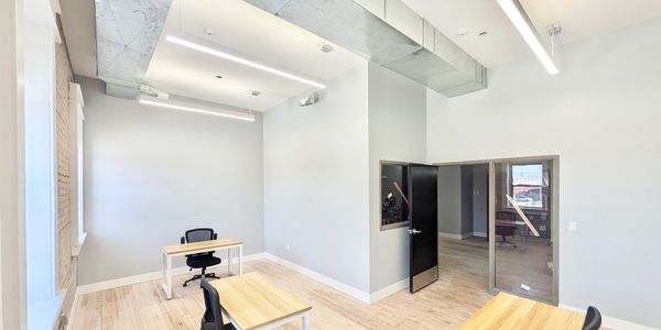 Bright modern office with wooden desks and black chairs.