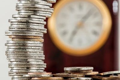 Stack of coins with a clock in the background