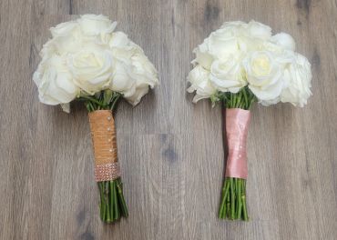 Two white rose bouquets with different handle wrappings.