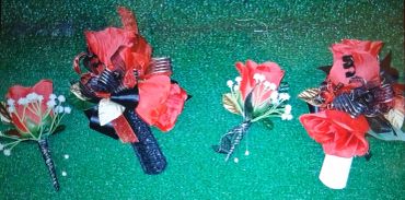 Red flower boutonnieres on a green background.