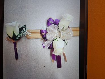 White rose corsages with purple ribbons.