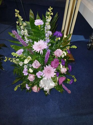 Bouquet of purple and white flowers with greenery on blue carpet.