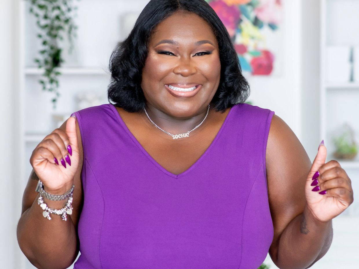 Smiling woman wearing a purple top and necklace.