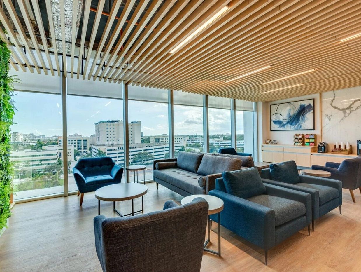 Modern office lounge with blue furniture and large windows.The Lobby