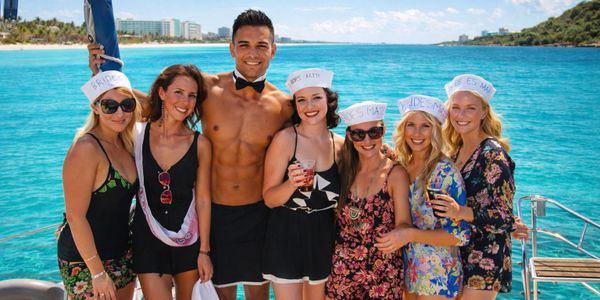 Group of friends celebrating on a boat with the ocean and cityscape in the background.