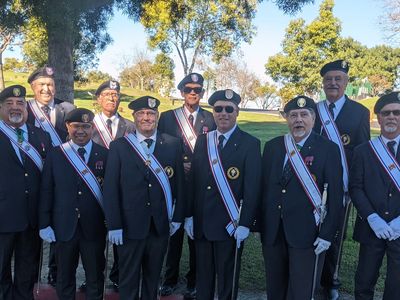 Group of veterans in uniform posing outdoors.