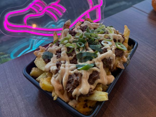 Loaded fries with meat, sauce, and green onions.