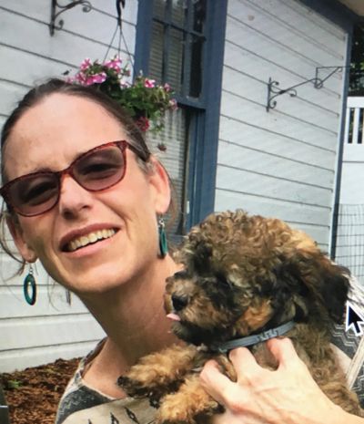 Woman smiling and holding a small fluffy dog.