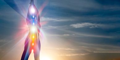 Silhouette of a person with glowing chakras against a sunset sky.