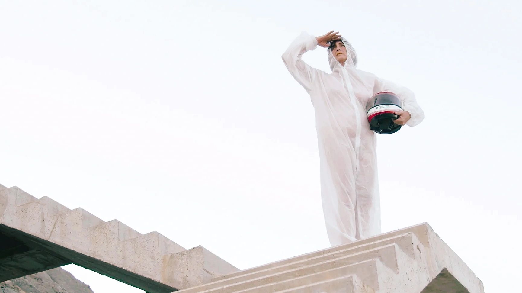 Persona con traje blanco y casco en una escalera de concreto.