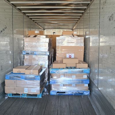 Pallets of boxed goods wrapped in plastic inside a truck trailer.
