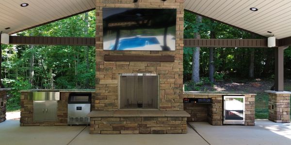 Outdoor covered patio with stone fireplace and mounted TV.