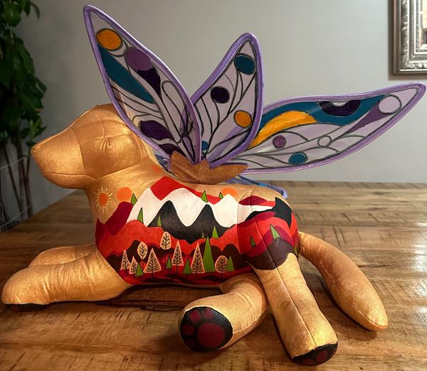 Colorful dog sculpture with butterfly wings on wooden table.