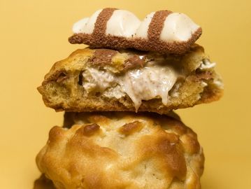Stack of creamy-filled cookies with a chocolate-striped topping against a yellow background.