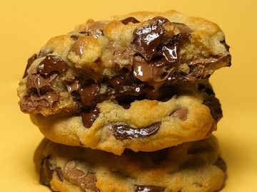 Stack of gooey chocolate chip cookies with melted chocolate.