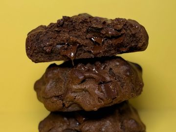 Stack of rich, gooey chocolate cookies against a yellow background.